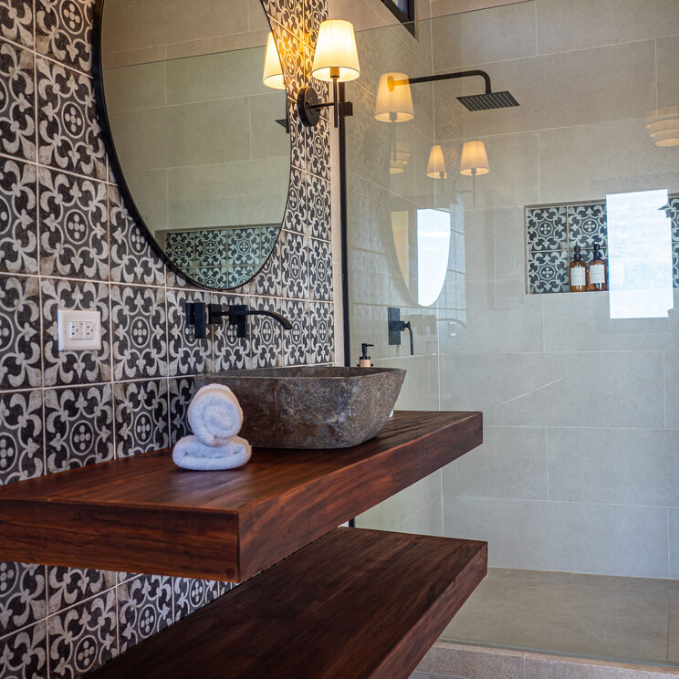 Modernes Badezimmer mit Natursteinwaschbecken, Holzregalen und gemusterten Fliesen in Boca Chica.