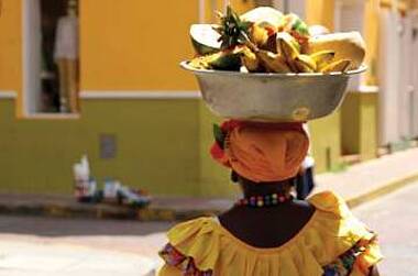Verkäuferin in tradioneller Kleidung mit Obstschale auf dem Kopf