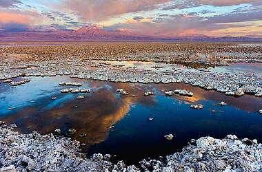 Salar de Atacama - Vulkane in rötlichem Sonnenlicht, See reflektiert den Himmel