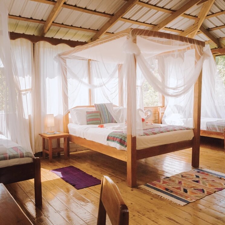 Innenansicht einer Cabana mit Himmelbetten, Moskitonetzen und Holzwaenden in San Ignacio, Belize.