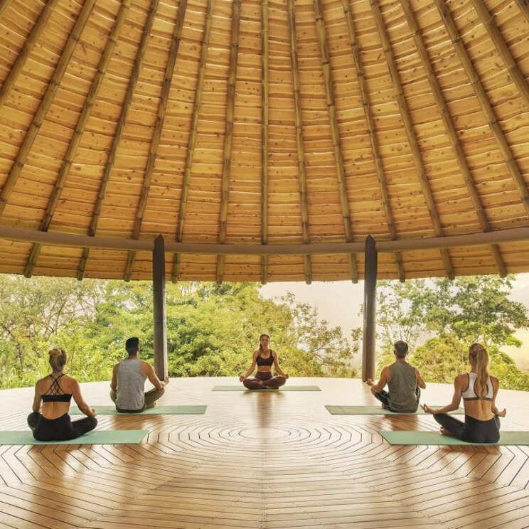 Yoga-Session im offenen Yoga-Pavillon des Origins Luxury Lodge in Costa Rica, umgeben von Natur.