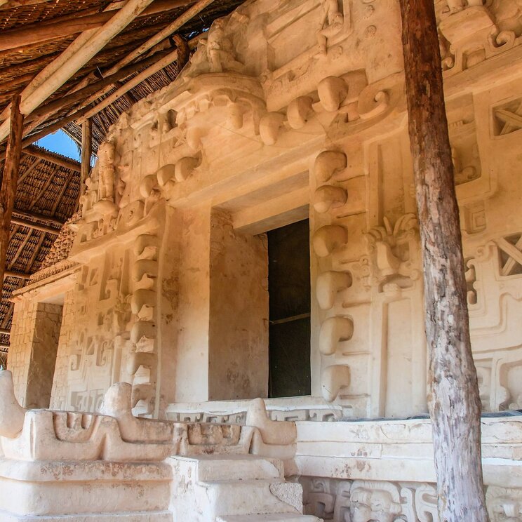 Detailansicht der gut erhaltenen Stuckfassade in der Maya-Ruine Ek Balam in Mexiko, geschützt durch ein Strohdach.