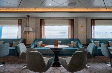Die stilvolle Lecture Lounge der Ocean Albatros mit bequemen Sesseln und großen Panoramafenstern mit Blick auf die Eislandschaft der Antarktis