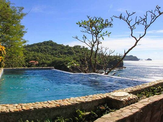  Blick auf den Infinity-Pool des Aqua Oceanfront Resort in Tola, Nicaragua, mit einer Panorama-Aussicht auf das Meer und die umliegende Natur.