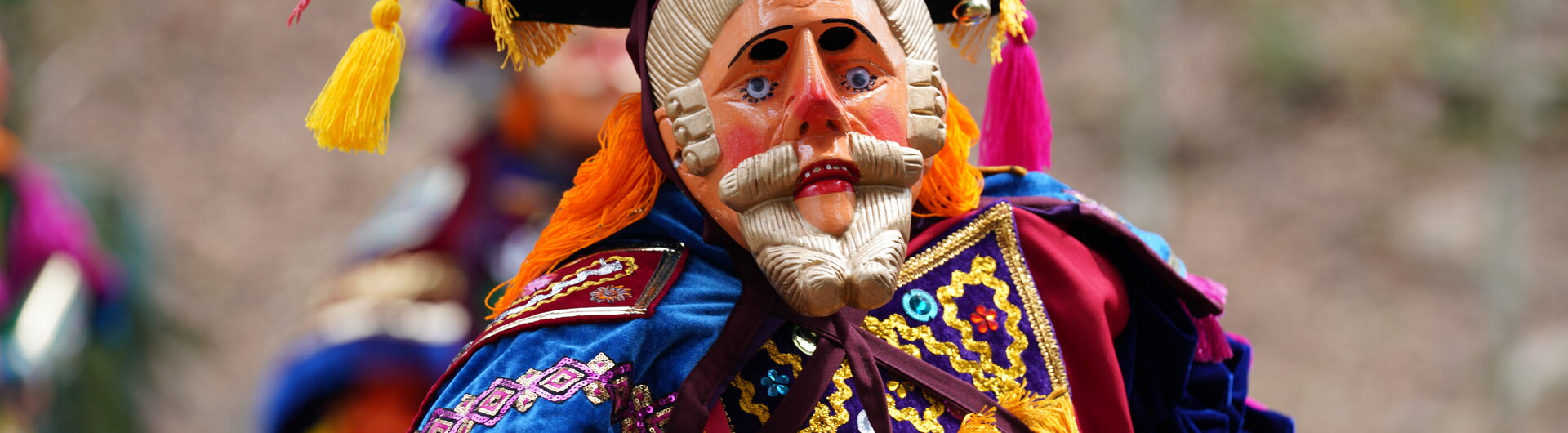 Person mit Holzmaske und buntem Kopfschmuck beim traditionellen Maya-Hirschtanz in San Antonio.