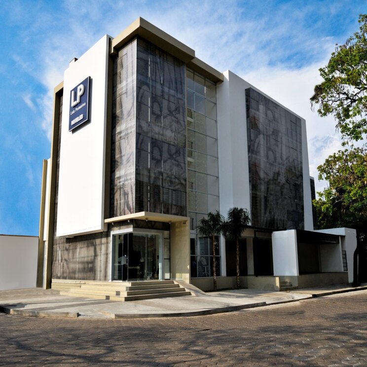 Moderne Aussenansicht des Hotels LP Santa Cruz mit weisser Fassade und grossen Glasfronten in Santa Cruz, Bolivien.