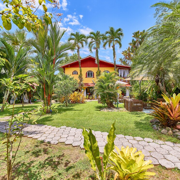 Gepflasterter Gartenweg zu einem gelb-roten Hotelgebäude in Costa Rica.