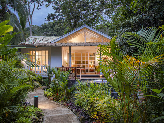 Beleuchteter Bungalow inmitten von dichtem tropischem Grün bei Dämmerung in Puerto Viejo, Costa Rica.
