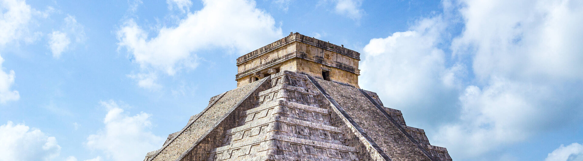 Die Pyramide El Castillo in Chichén Itzá, Mexiko, ein ikonisches Maya-Bauwerk umgeben von grüner Landschaft.