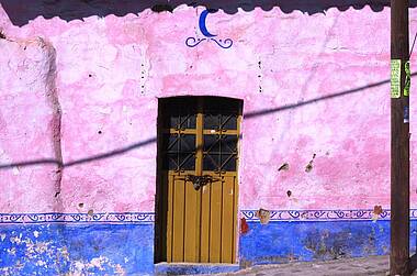 Holztür in rosa- und blaufarbener Fassade